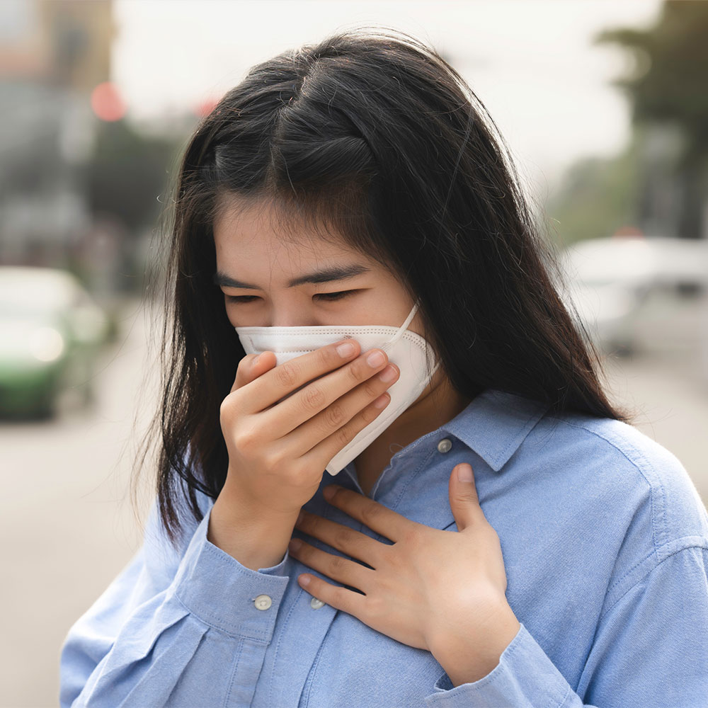 Cô gái đeo mặt nạ và dùng tay che mặt